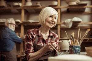 Senior woman painting clay pot at workshop