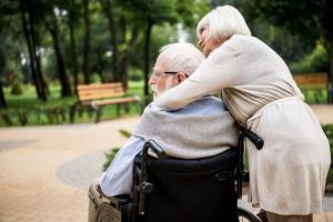 senior woman with her arms around senior man in wheelchair