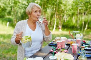Senior woman at picnic table drinking water with lemon