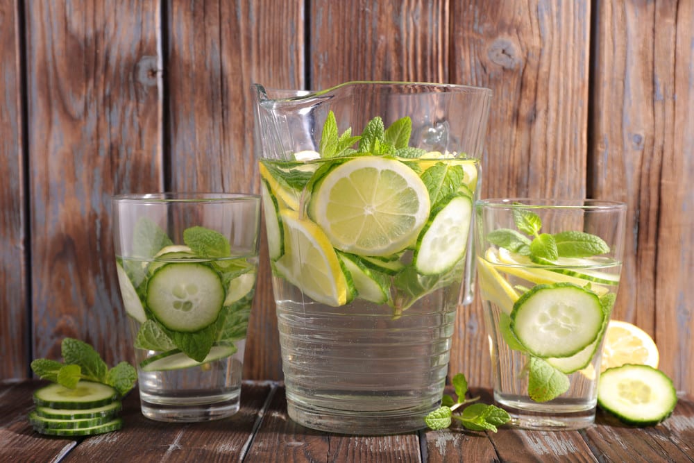 Pitcher of water and two glasses of water with lemon and cucumber slices