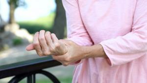 Close-up of senior woman touching wrist with other hand