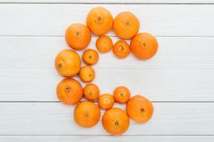 Oranges and tangerines forming the letter C on white wood background