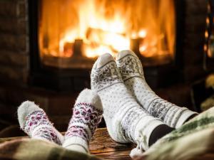 Two pairs of feet (one adult, one child) in fair isle socks in front of the fireplace