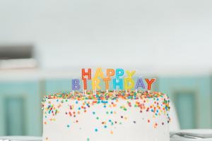 Birthday cake with sprinkles and candles reading "happy birthday"