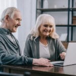 Senior man and woman smiling at laptop screen