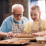 Senior man and young girl baking cookies together
