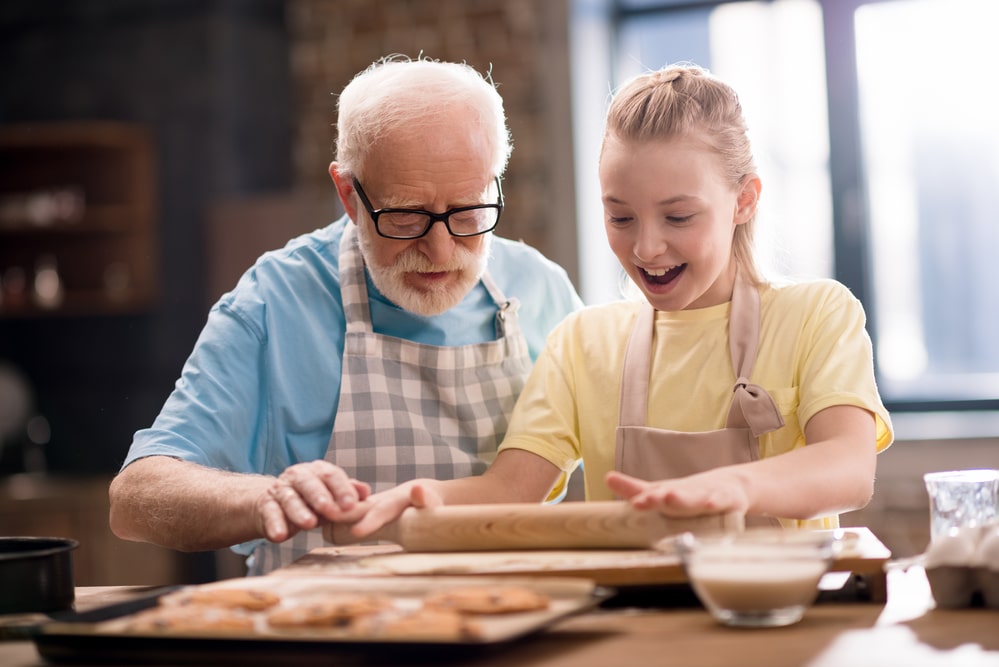 Senior man and young girl baking cookies together