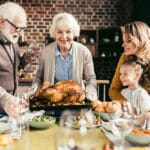 Smiling senior woman holding turkey surrounded by family