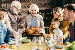 Smiling senior woman holding turkey surrounded by family