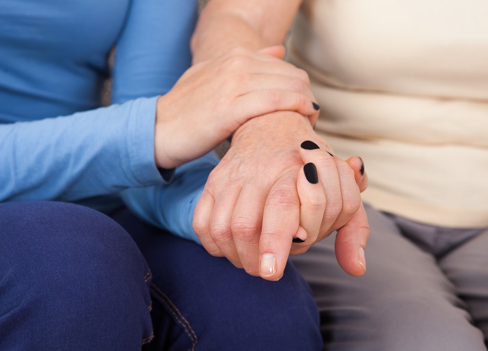 Young female hand holding older female hand