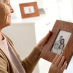 Elderly woman with frame family portrait