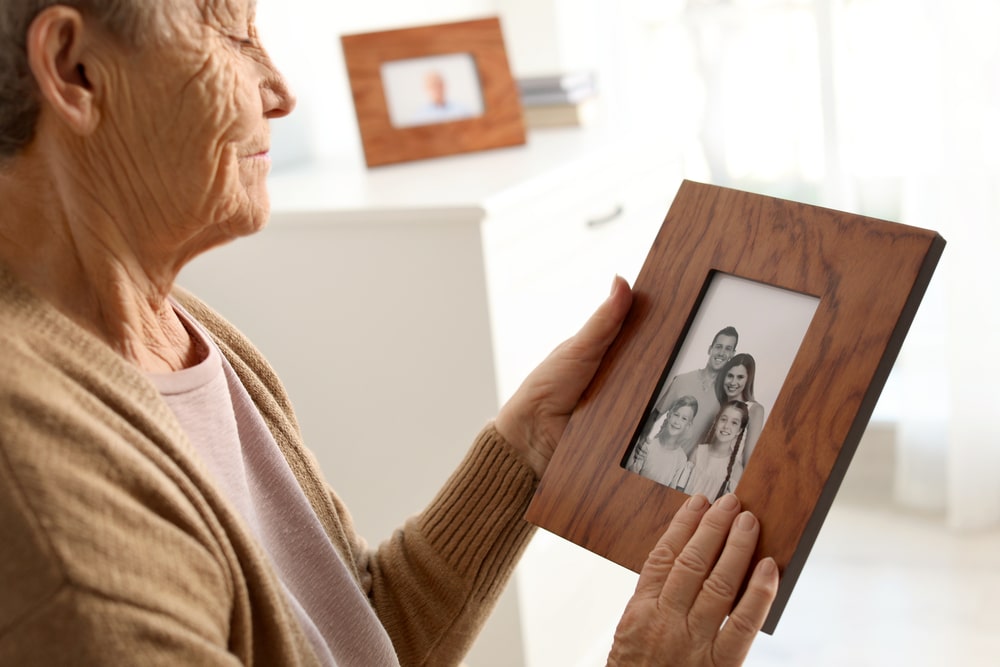 Elderly woman with frame family portrait