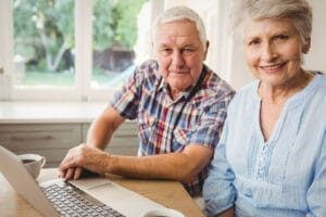 Two smiling seniors using laptop together