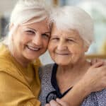 Two senior women hugging and smiling